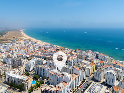 Vista aérea da vila costeira de Armação de Pêra com oceano azul, praia e edifícios residenciais no Algarve, Portugal