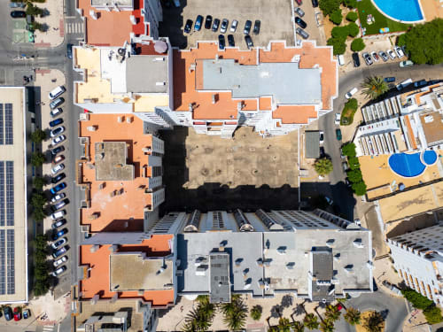 Vista aérea do complexo hoteleiro Happy Nest AL em Armação de Pêra com telhados de barro, pátios, piscinas e estacionamento