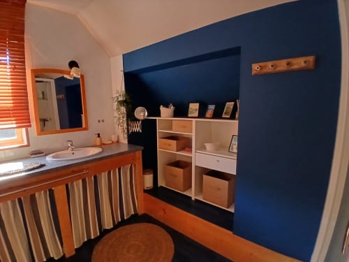 Chambre moderne à Ma Cabane du Canada à Combray avec mur d'accent bleu, mobilier en bois, lavabo et équipements partagés
