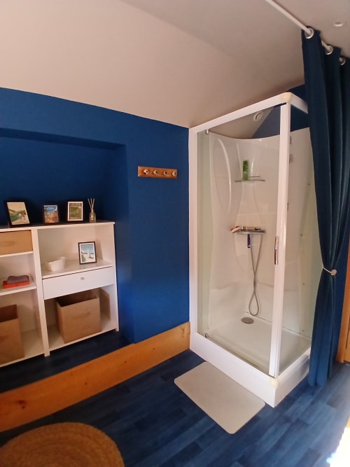 Salle de bain moderne à Ma Cabane du Canada, Combray, avec murs bleus, douche et rangements en bois.