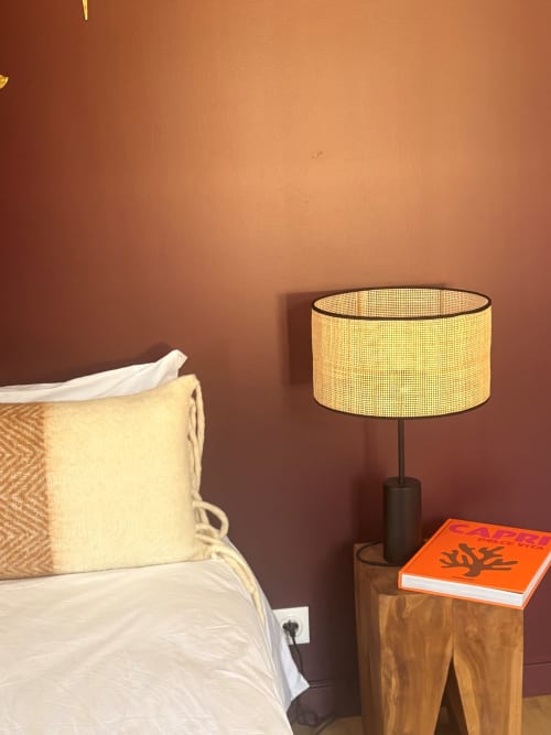 Cozy bedroom corner with yellow lamp, cream pillow, and orange book on wooden nightstand at Maisons Valmer hotel in Le Havre