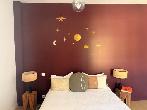 Bedroom with burgundy accent wall featuring celestial decor, moon and star details, nautical-themed nightstands with lamps,