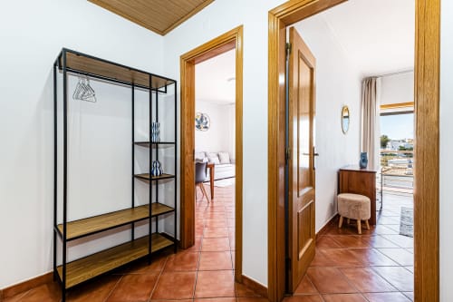 Corredor do apartamento Happy Nest AL Mar Azul com portas de madeira, piso em terracota e prateleiras modernas em Armação de Pêra