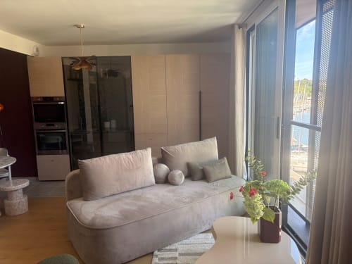 Penthouse moderne de Maisons Valmer au Havre avec canapé crème, baies vitrées vue mer, cuisine et panorama sur le port.