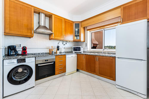Cozinha moderna com armários de madeira, bancadas de granito, eletrodomésticos de aço inoxidável e vista para a janela no Happy Nest AL