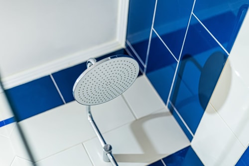Chuveiro moderno em banheiro com azulejos azuis e brancos na Happy Nest AL, Armação de Pêra