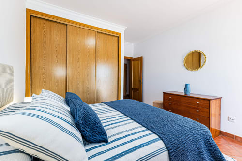 Quarto Mar Azul no Happy Nest AL em Armação de Pêra com guarda-roupa em madeira, roupa de cama com listras azuis e vista para o jardim