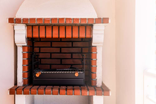 Lareira decorativa em tijolo com insert de grelha preta no apartamento Happy Nest AL, Armação de Pêra, Portugal