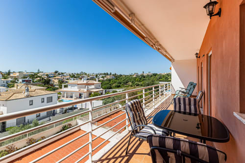 Varanda ensolarada em terracota no Happy Nest AL em Armação de Pêra com espreguiçadeiras, vista para o jardim e paisagem da vila costeira