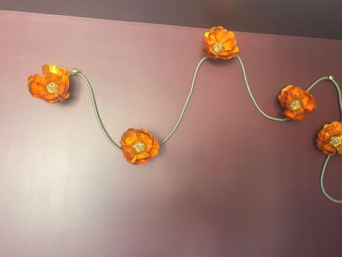 Orange decorative flowers with green stems on pink wall at Maisons Valmer hotel in Le Havre