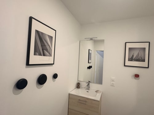 Bathroom with vanity sink, mirror, and framed nautical artworks in Le Havre apartment.
