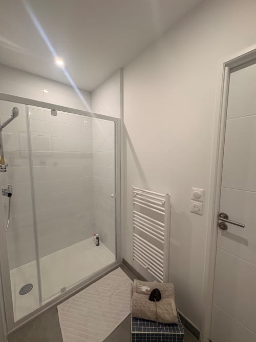 Modern bathroom with walk-in shower, heated towel rack, and white tile walls at Maisons Valmer, Le Havre