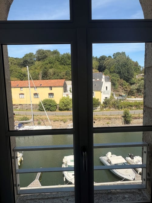 View from An heol penthouse at Maisons Valmer showing sailboats in Le Havre marina with yellow building and trees