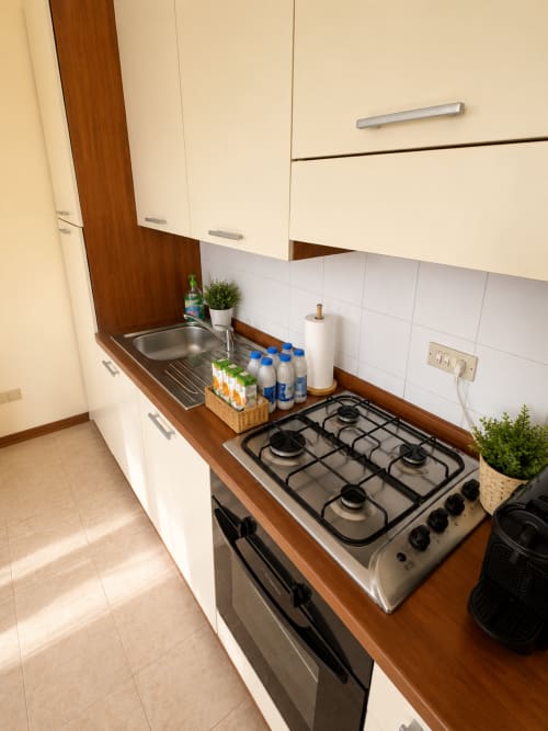 Cucina moderna nell'appartamento Bicocca Flat Milano con fornello a gas, lavandino, mobili bianchi e piano in legno