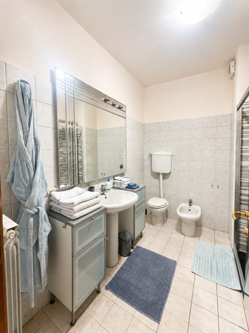 Bagno moderno nell'appartamento Bicocca Flat a Milano, con lavabo, WC, bidet, specchio e pareti piastrellate