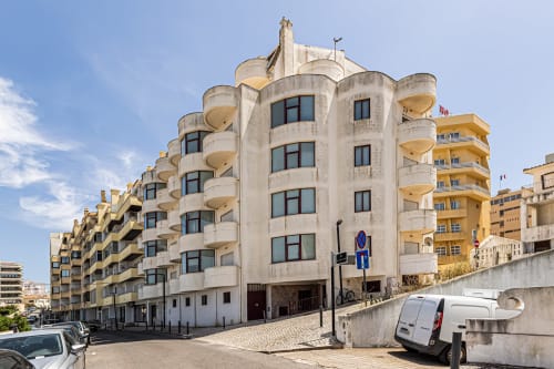 Edifício de apartamentos Happy Nest AL com varandas curvilíneas em Portimão, Portugal, apresentando arquitetura moderna curva e vista da cidade