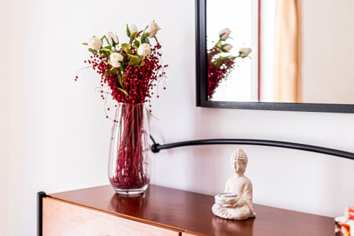 Decoração elegante do apartamento Happy Nest AL com arranjo floral de frutos vermelhos, estátua de Buda e obra de arte emoldurada em Marina Rocha