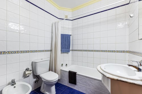 Banheiro moderno em Happy Nest AL em Portimão com azulejos brancos, acentos azuis, vaso sanitário, pia e banheira