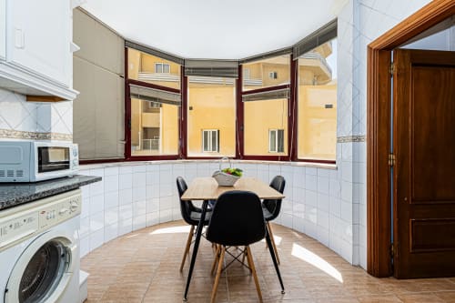 Cozinha do apartamento Marina Rocha com mesa de jantar, varanda com vista para a cidade, máquina de lavar e eletrodomésticos modernos no Happy Nest AL
