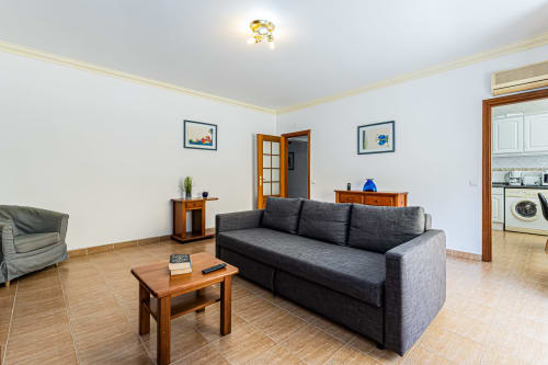 Sala de estar moderna no apartamento Marina Rocha da Happy Nest AL, Portimão, com sofá cinzento e móveis em madeira