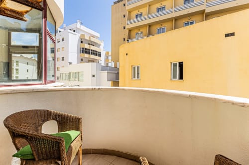 Cadeira de vime com almofada verde no terraço da varanda do apartamento Marina Rocha no Happy Nest AL em Portimão, com vista para a cidade