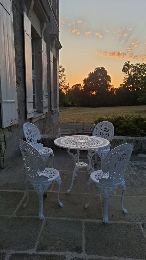 Chaises blanches ornées et table sur la terrasse du Château de Saint Thomas, coucher de soleil sur les champs et les arbres, Saint-Étienne-de-Montluc