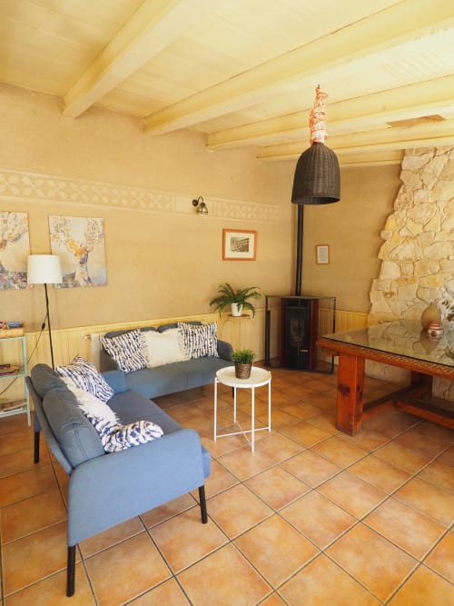 Cozy living room at Senda del Duratón Apartments with blue seating, terracotta floors, and rustic stone fireplace in Sebúlcor