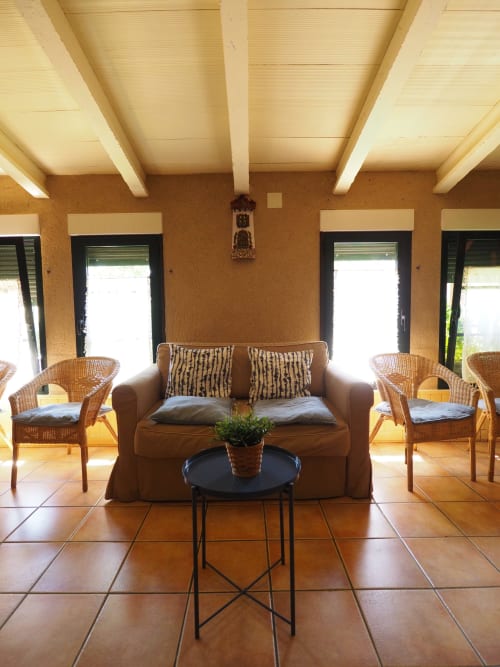 Bright sunlit lounge at Rural Senda del Duratón with beige sofa, wicker chairs, and terracotta tile floor