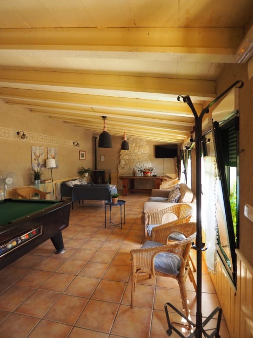Spacious common lounge at Senda del Duratón Apartments with wooden beams, wicker chairs, pool table, and rustic décor