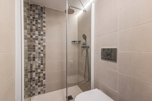 Banheiro moderno com parede de destaque em azulejos mosaico na pousada Happy Nest AL em Pêra, Portugal