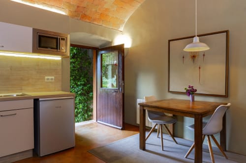 Cocina y comedor modernos con mesa de madera, sillas y puerta al jardín en Apartmentos Rectoria de Regencós