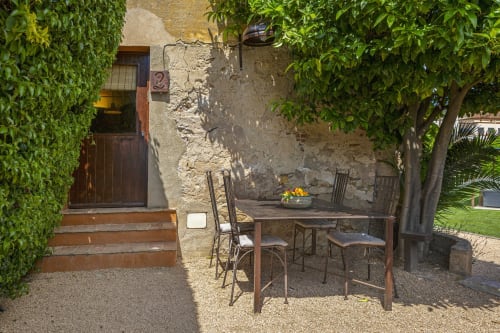 Patio sombreado de los Apartmentos Rectoria de Regencós con mesa de comedor, sillas y paredes cubiertas de hiedra