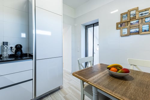 Cozinha moderna na casa de campo Casa Passarinho em Happy Nest AL, Pêra, com armários brancos, mesa de madeira e fruteira