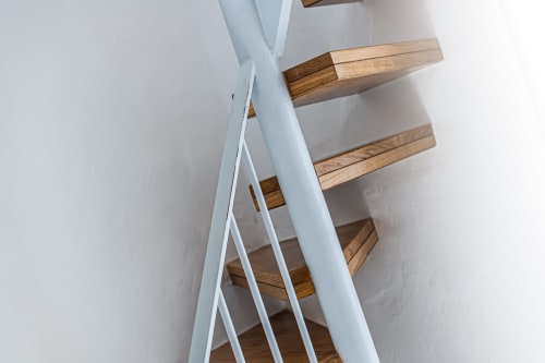 Escadaria em espiral moderna com corrimãos brancos e degraus em madeira na pousada Happy Nest AL em Pêra, Portugal