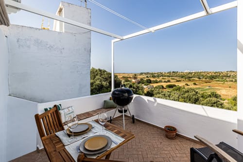 Terraço da Casa Passarinho na Happy Nest AL em Pêra, Portugal com mesa de jantar, churrasqueira e vista para a zona rural