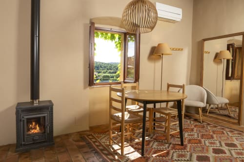 Salon cosy de l'appartement à Rectoria de Regencós avec cheminée, table à manger et vue sur le jardin