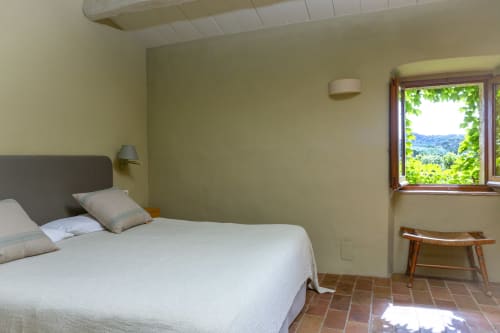 Chambre lumineuse aux Apartmentos Rectoria de Regencós avec lit blanc, vue sur le jardin, carrelage en terre cuite