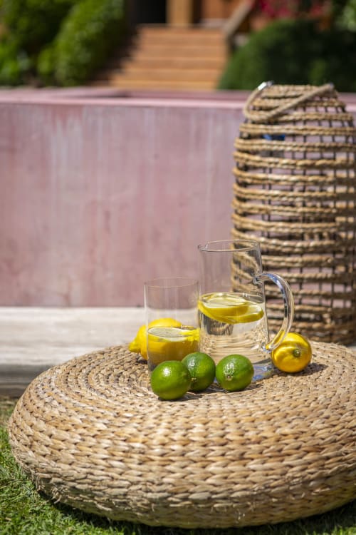 Table de jardin à la Costa Brava avec eau citronnée, citrons verts et chaises tissées en arrière-plan