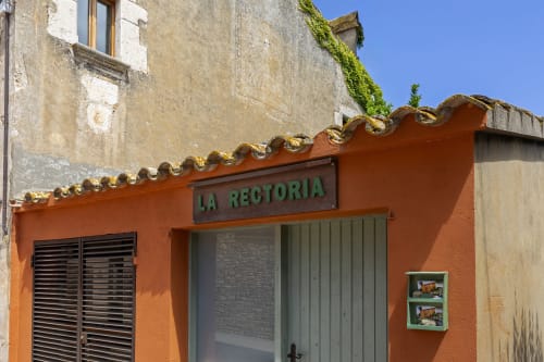 Façade d'une charmante maison orange vif avec l'enseigne 'La Rectoria' aux Apartmentos Rectoria en Costa Brava
