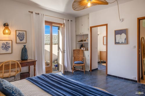 Spacieuse chambre de villa à Centuri, Corse avec vue mer, literie rayée bleue, mobilier bois et équipements modernes
