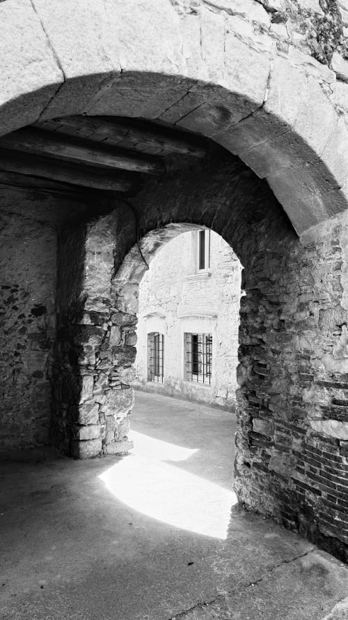 Passage voûté en pierre menant à une maison blanche du complexe de maisons de campagne de la Costa Brava à Regencós