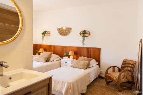 Chambre lumineuse à la villa La Conciergerie du Cap Corse avec lits jumeaux, tête de lit en bois et salle de bains attenante à Centuri