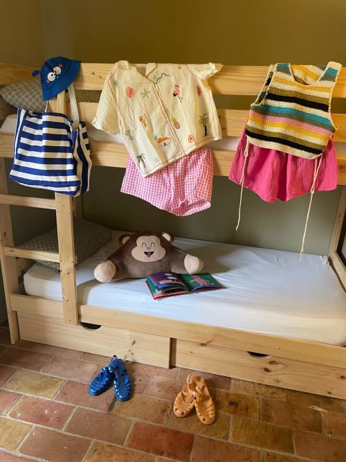 Lit superposé en bois pour enfant avec vêtements colorés et jouets dans un gîte de la Costa Brava