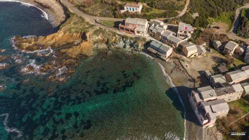 Vue aérienne de la Villa Annonciade à Centuri, Cap Corse, avec ses eaux turquoise et sa situation spectaculaire en falaise côtière