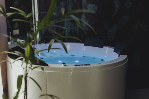 Lussuosa vasca idromassaggio con acqua blu e getti presso l'hotel esclusivo Oltre a Palermo, circondata da piante verdi