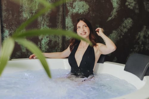Donna che gode di un bagno termale presso l'hotel boutique esclusivo Oltre a Palermo, con parete ricoperta di muschio e piante verdi