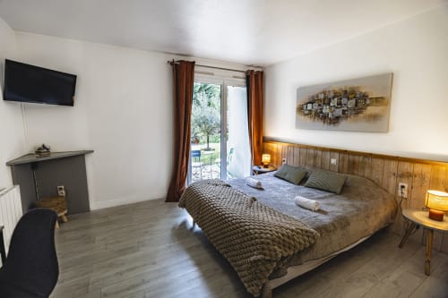 Spacieuse chambre double à l'Hôtel De La Bonnheure avec vue sur le jardin, TV, tête de lit en bois et accès à la terrasse