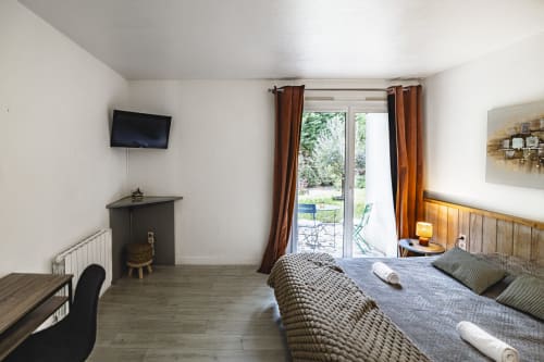 Spacieuse chambre double à l'Hôtel De La Bonnheure avec vue jardin, TV, mobilier moderne et portes-fenêtres donnant sur la terrasse
