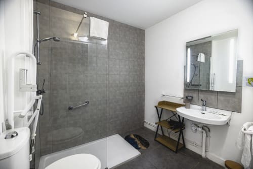 Salle de bain moderne de l'Hôtel De La Bonnheure à Bracieux avec douche à l'italienne, lavabo et accessibilité pour fauteuil roulant
