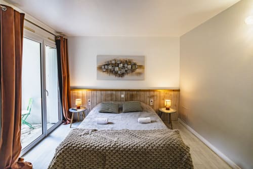 Chambre double moderne à l'Hôtel De La Bonnheure à Bracieux avec tête de lit en bois, balcon vue jardin et éclairage chaleureux
